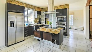 A modern kitchen with a central island, stainless steel appliances, and a marble backsplash.