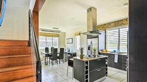 A modern kitchen with a central island, black cabinets, and a stainless steel range hood.