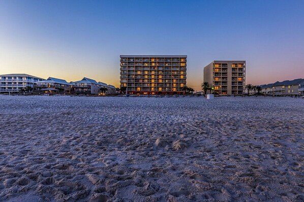 A beachfront hotel with multiple buildings, a sandy beach, and a clear sky.