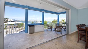 A spacious balcony with a view of the sea, a ceiling fan, and a dining area with chairs and a table. - Bay Views- Private Pool- Great Location- 5BRBlue Horizon (Fort Myers Beach)