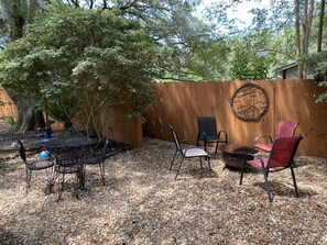 A patio with a round table and chairs, surrounded by a wooden fence and trees. - The Retreat (Austin)