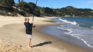 Escena de playa con alguien pescando.