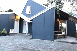 En modern byggnad med en blå fasad, en vit dörr och en träbänk utanför.