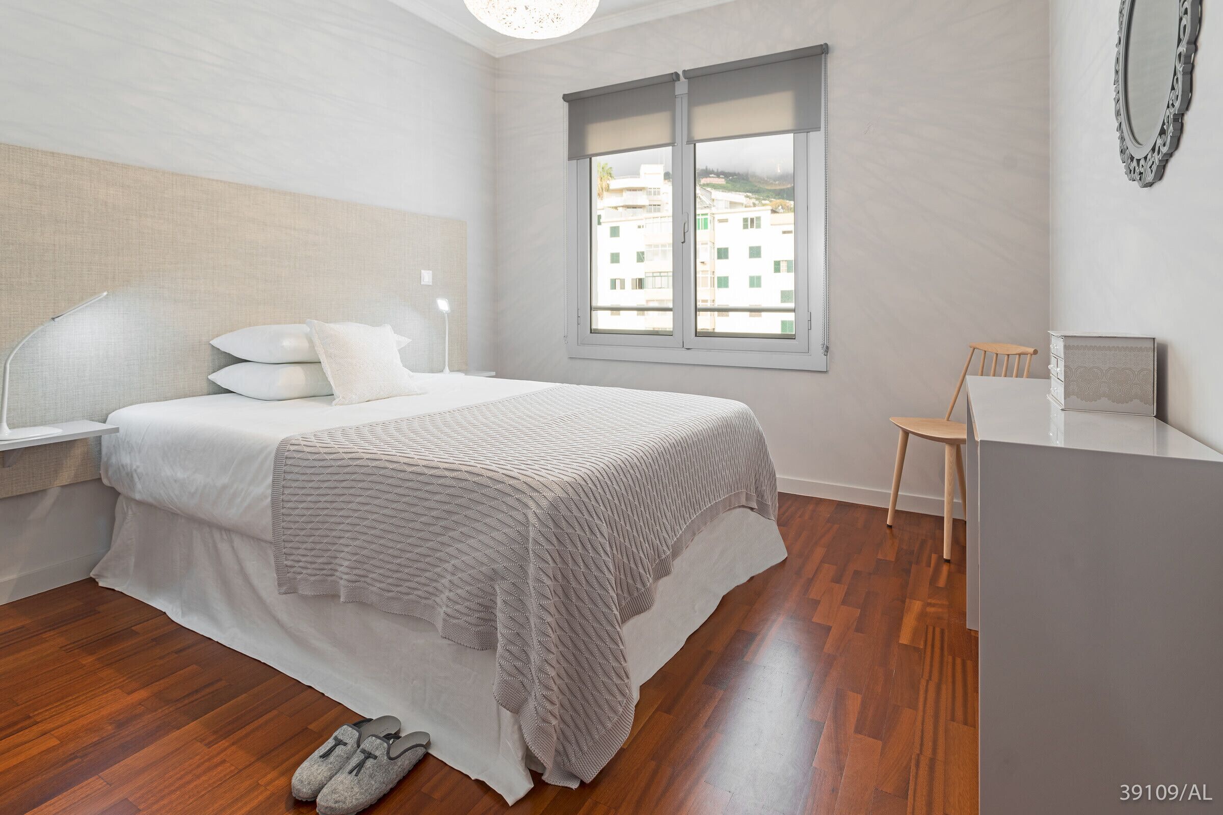 A bedroom with a bed, a window, a chair, and a desk.