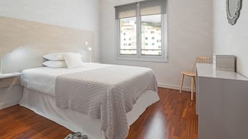 A bedroom with a bed, a window, a chair, and a desk.