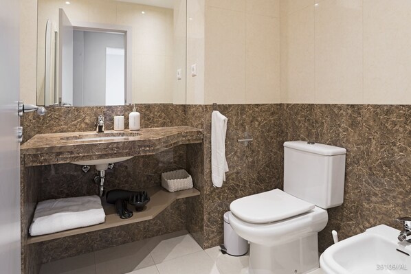 A modern bathroom with a marble sink, a toilet, and a bidet. - Santa Catarina I, modern city apartment (Funchal)