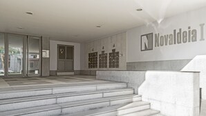 A modern building entrance with a glass door, a staircase, and a wall with a sign reading "Nacionalde".