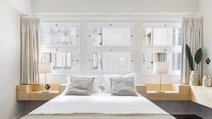 Ein Schlafzimmer mit einem großen Bett, zwei Nachttischen, einem Vorhangfenster und einer Nachttischlampe.