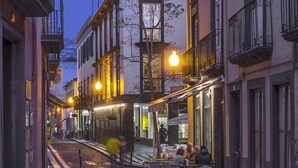 A narrow street with buildings on both sides, outdoor seating for cafes, and a cobblestone path. - Downtown Funchal Apartments 1C Cedros. (Funchal)