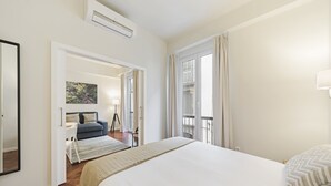 A bedroom with a large bed, a desk, a chair, and a balcony with curtains. - Downtown Funchal Apartments 1C Cedros. (Funchal)