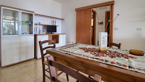 A compact kitchen with a dining table, chairs, and a cabinet with glass doors.