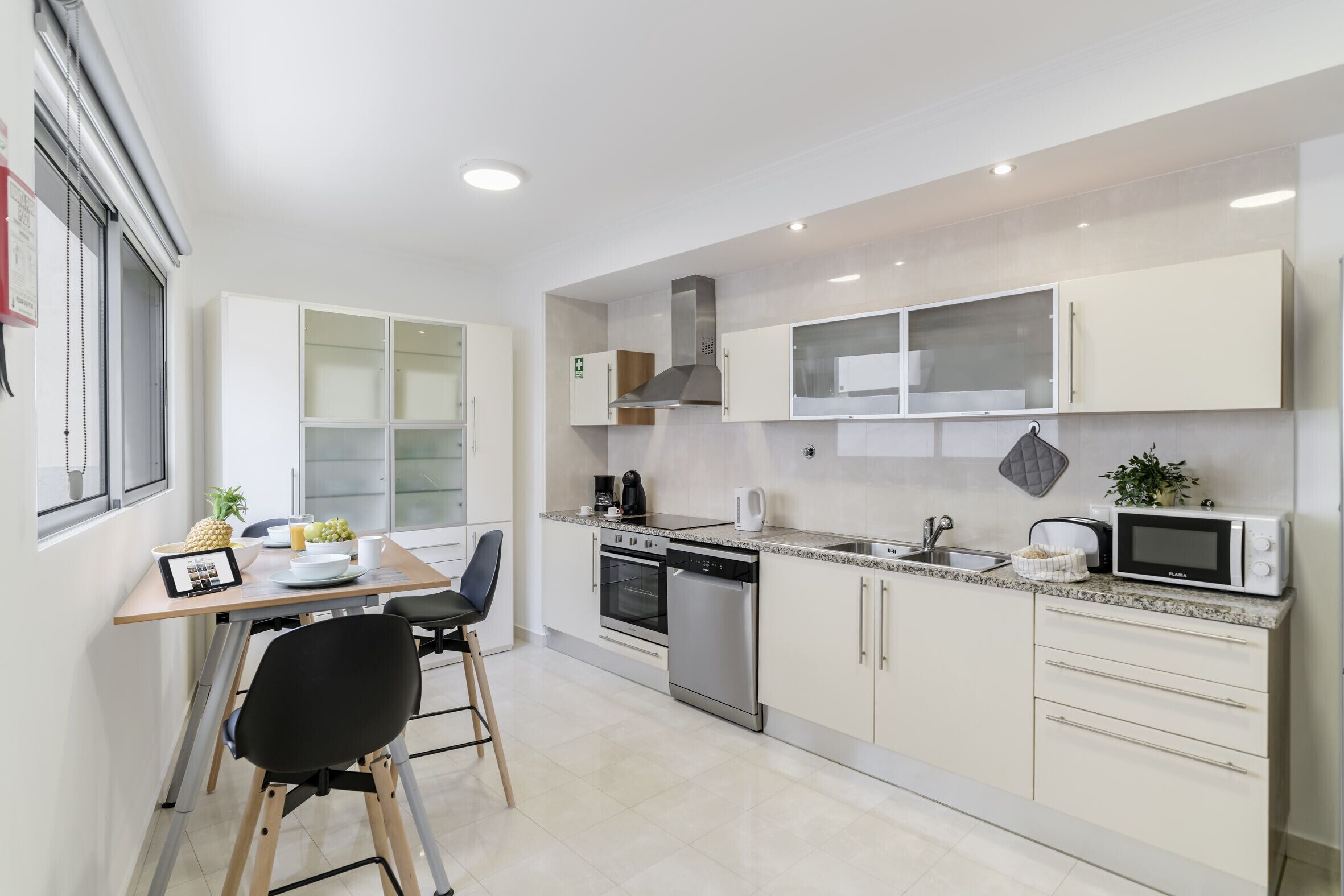 A modern kitchen with white cabinets, stainless steel appliances, and a dining area with a table and chairs.