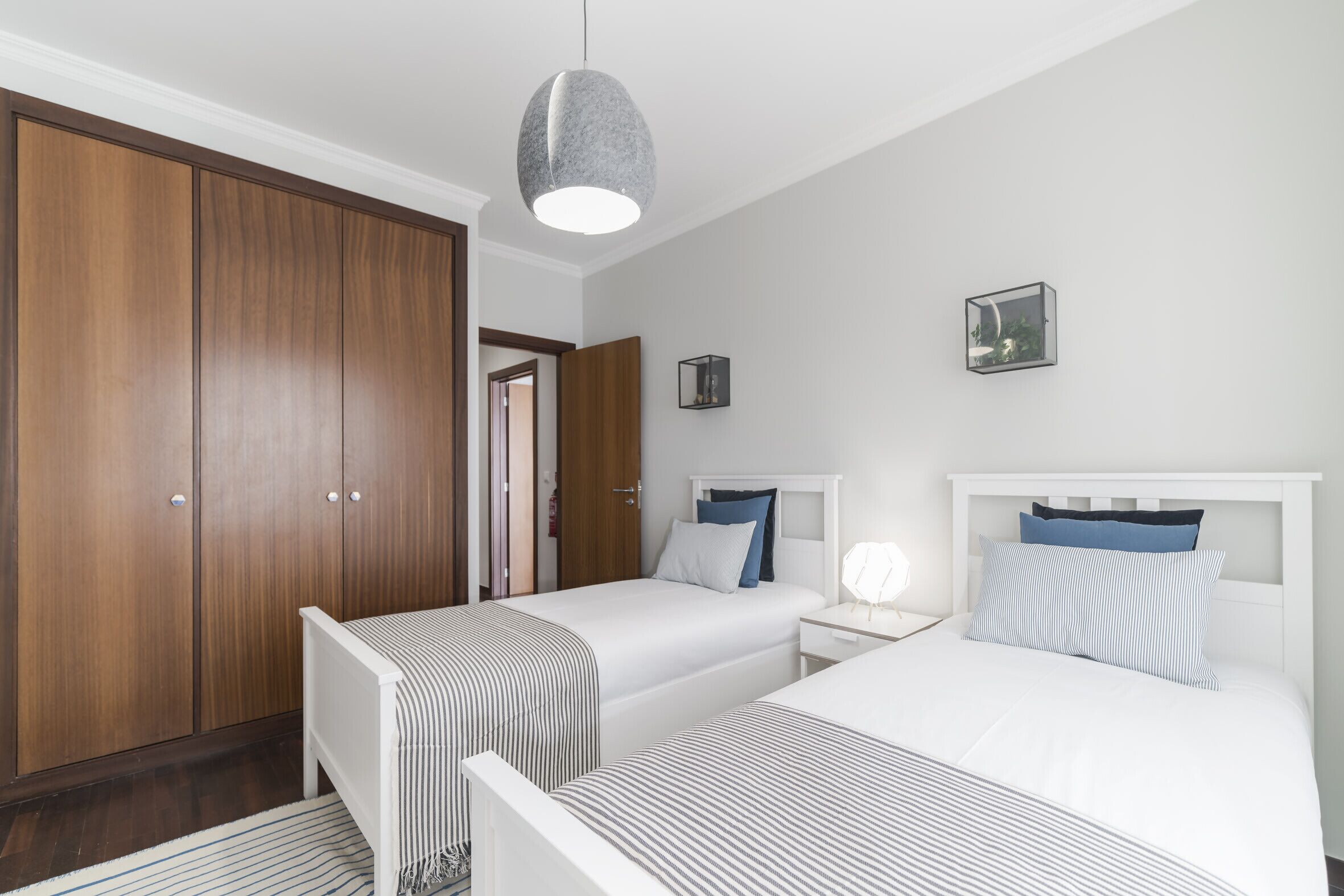 Een slaapkamer met twee bedden, een kledingkast en een nachtkastje met een lamp.