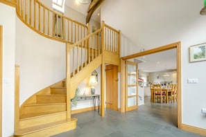 A wooden staircase leading to a second floor with a dining area in the background.