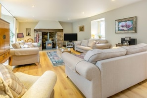 A cozy living room with a stone fireplace, comfortable seating, and a television.