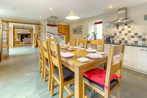 A dining area with a wooden table set for four, surrounded by wooden chairs with cushioned seats.