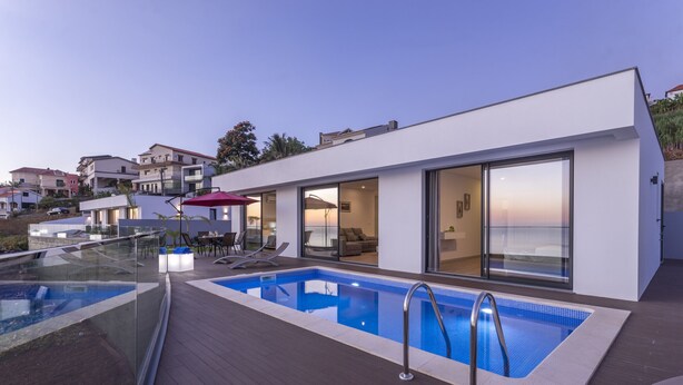 Una casa moderna con piscina, puertas de cristal y zona de patio.