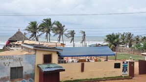 A coastal building named 'Sango House' with a beach view, palm trees, and a blue tarp-covered area. - Villa D' Coco (Accra)