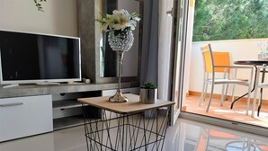 A modern living room with a flat-screen TV, a wooden coffee table, and a decorative vase with flowers. - Apartment Kristina 400 m from the sandy beach + air condition + WiFi +dishwasher (Medulin)