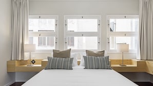 Una camera da letto con un letto grande, due comodini e tre finestre con tende.