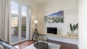 Un soggiorno moderno con un tavolo in vetro, un televisore a schermo piatto e un'ampia finestra con tende.