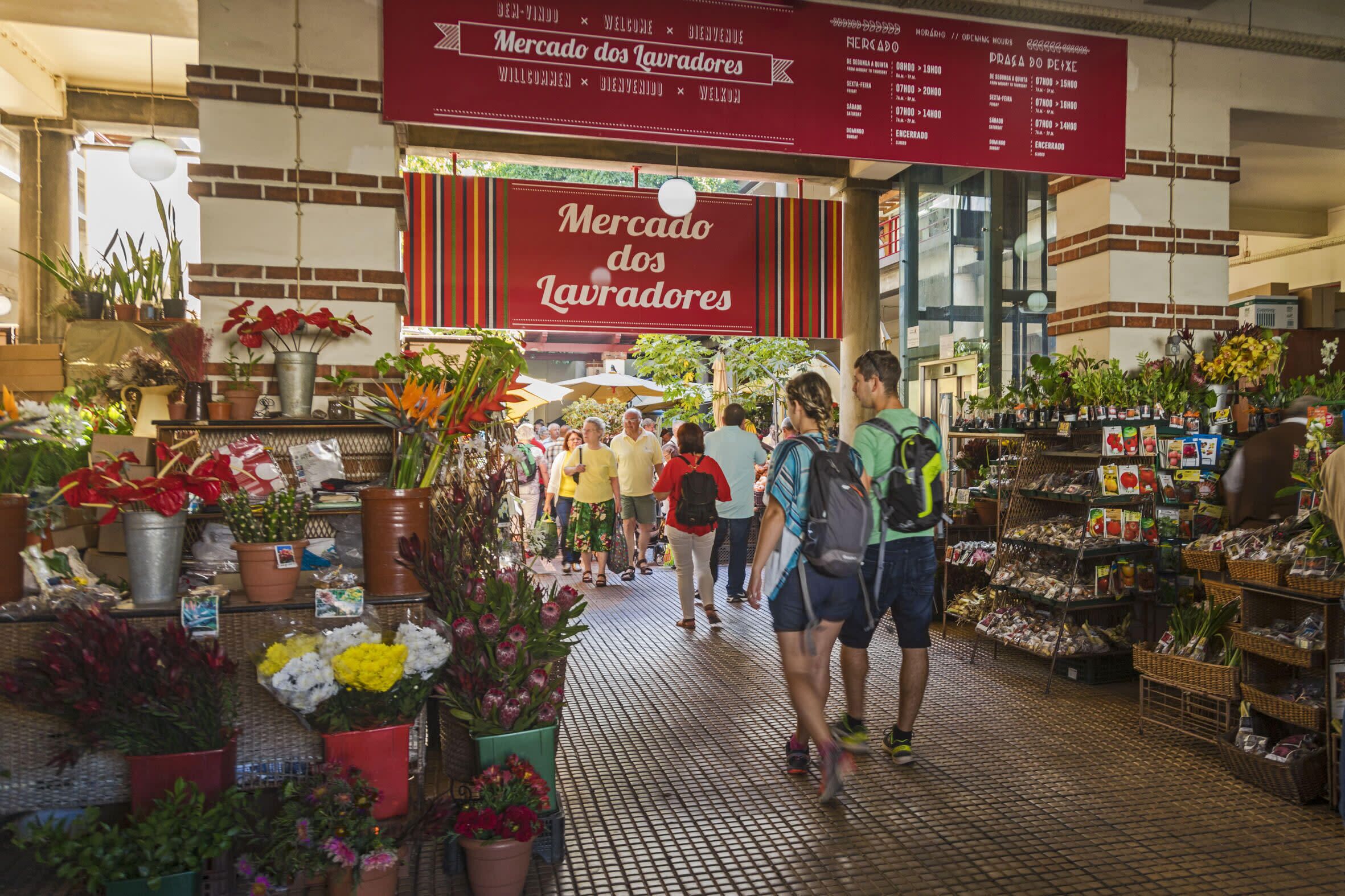 Un mercado interior concurrido, con varios puestos que venden flores y plantas.