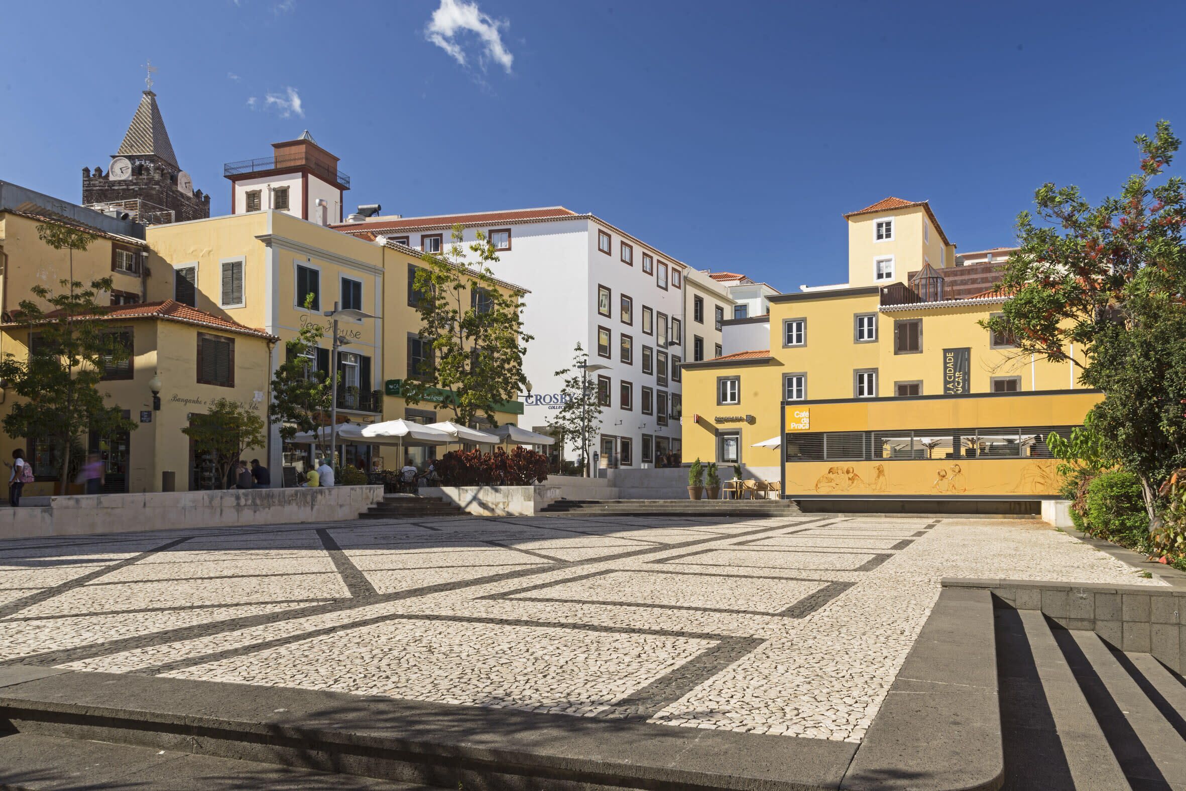 A plaza with cobblestone pavement, surrounded by buildings with commercial establishments.