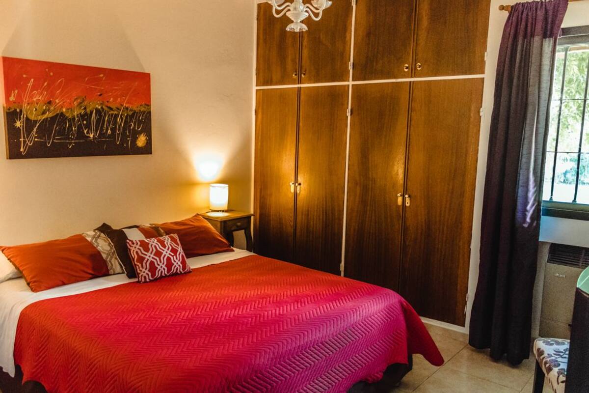 Een slaapkamer met een groot bed, een houten garderobe, een nachtkastje en een schilderij aan de muur.