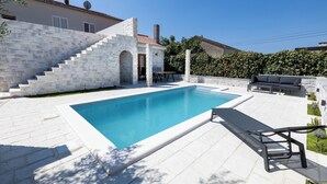 A swimming pool with stone steps leading up to a door, surrounded by a white tiled patio and a hedge. - Cozy Apartment • Pool • close to Trogir & Airport (Trogir)