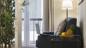 Ein modernes Wohnzimmer mit einem Laptop auf einem Sofa, einer Holtschale mit Früchten und einer Stehlampe.
