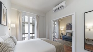 Ein Hotelzimmer mit einem großen Bett, einer Couch, einem Spiegel und einer Tür zu einem Balkon.