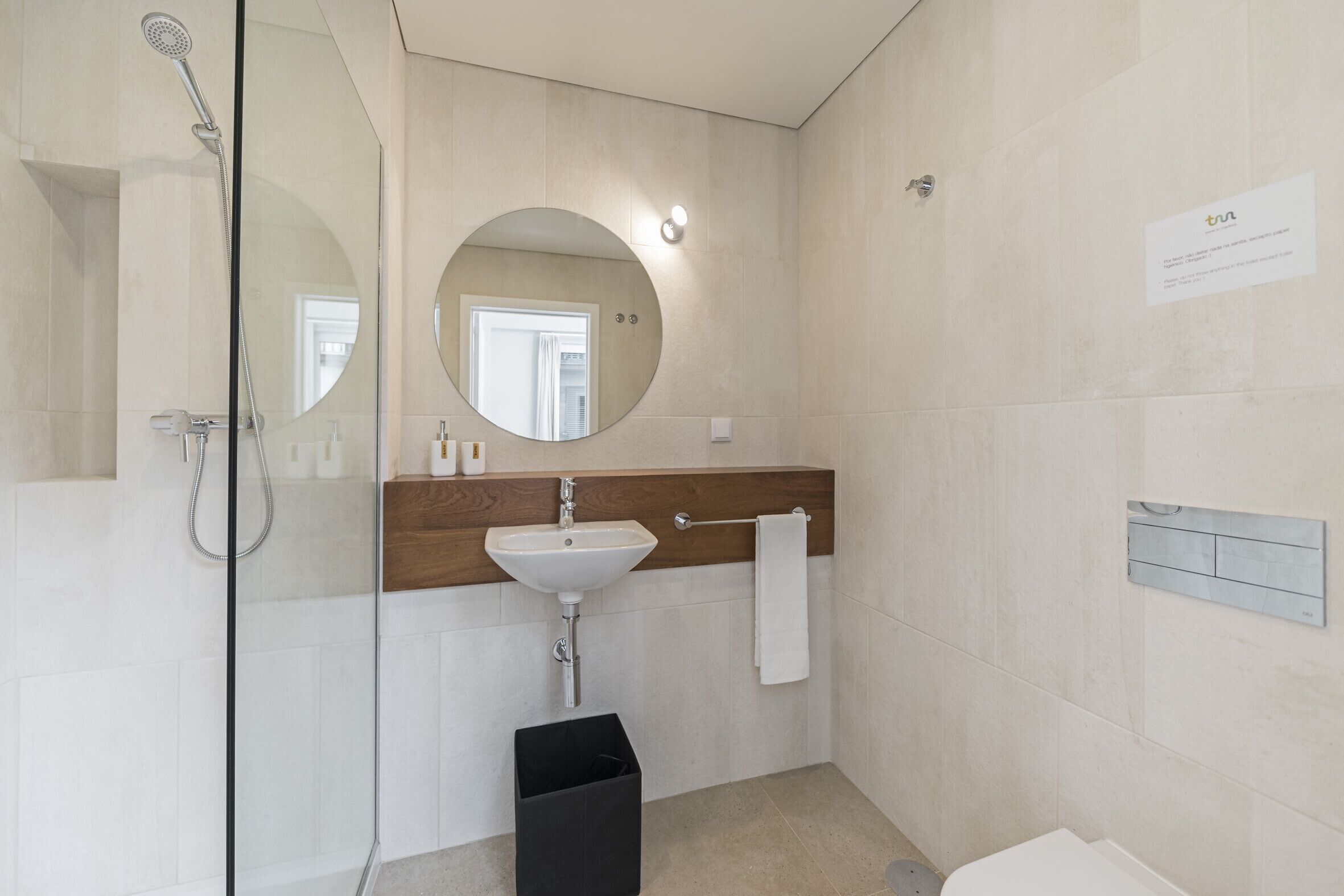 Une salle de bain moderne avec une douche à parois de verre, un lavabo blanc et un meuble-lavabo en bois.