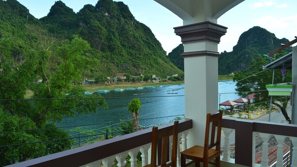 A balcony with a view of a river and mountains. - Son Doong Riverside Homestay (Phong Nha)