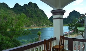 A balcony with a view of a river and mountains. - Son Doong Riverside Homestay (Phong Nha)