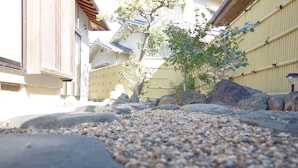 A traditional Japanese garden with a gravel path, rocks, and a small tree. - BOND - Hostel (Shimamoto)