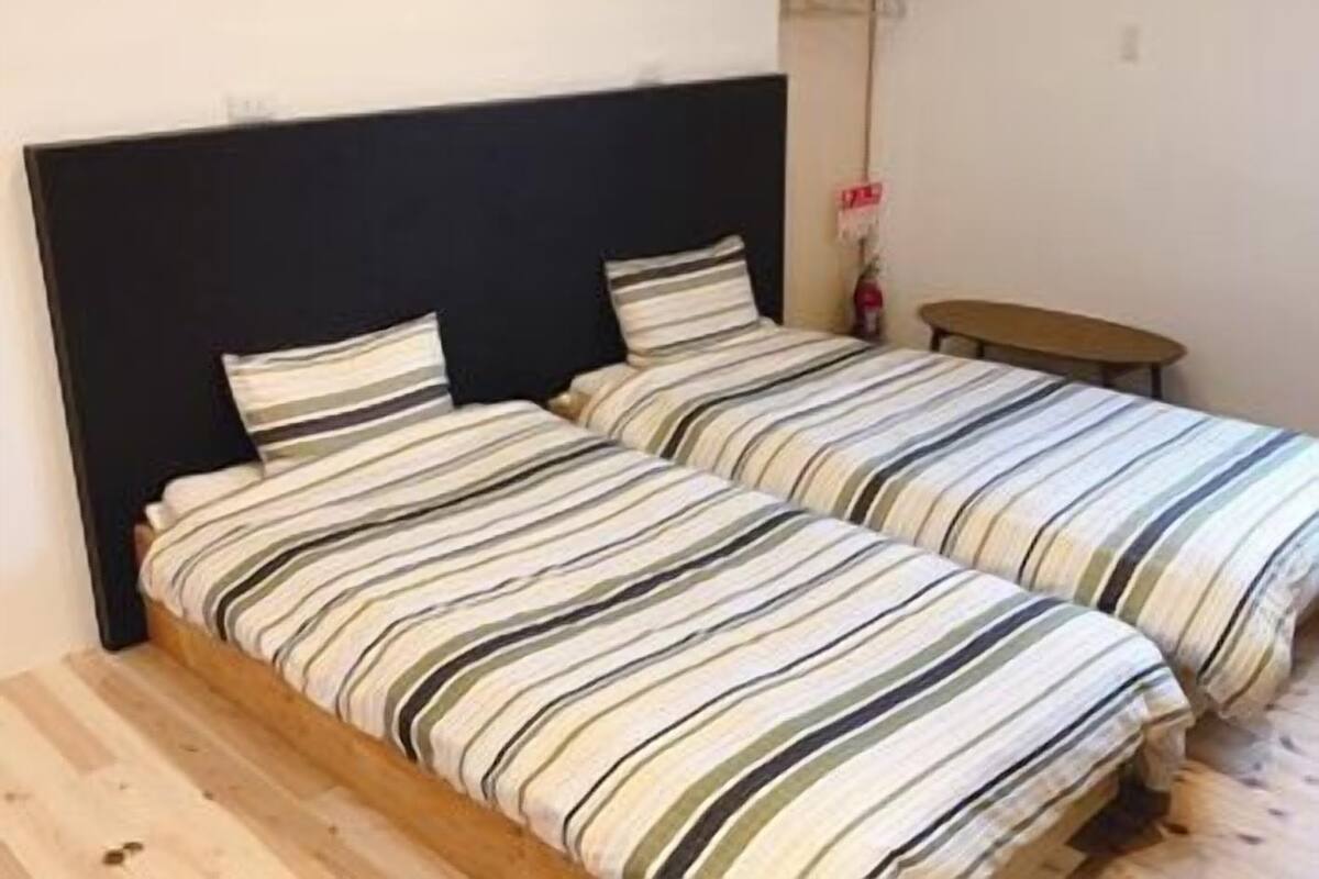 Ein Schlafzimmer mit zwei Einzelbetten, einem hölzernen Kopfteil und einem kleinen Holztisch.