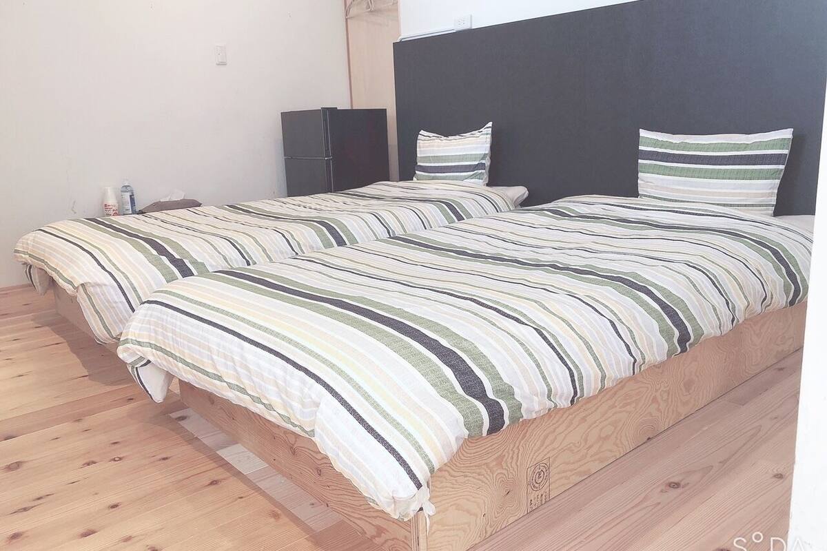 Ein Doppelbett mit gestreifter Bettwäsche, ein dunkles Kopfteil und ein Holzboden.