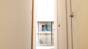 A corridor with sliding doors leading to a room with a view of a garden. - BOND - Hostel (Shimamoto)