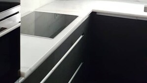 Eine moderne Küche mit weißen Schränken, einer schwarzen Arbeitsplatte und einem Fenster über der Spüle.
