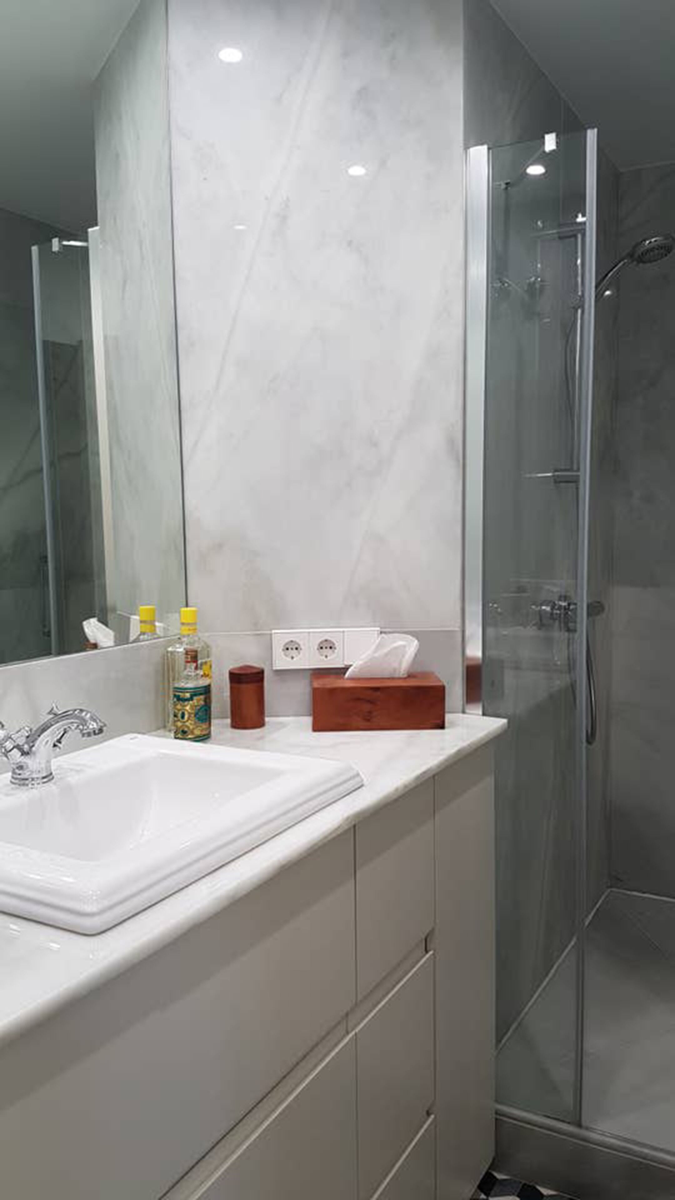 A modern bathroom with a large mirror, a white sink, and a glass shower enclosure.