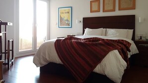 Ein Schlafzimmer mit einem großen Bett, einem hölzernen Kopfteil, einer Schiebetür und drei gerahmten Bildern an der Wand.