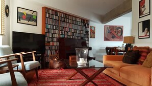 Ein Wohnzimmer mit einer großen Bücherwand, einem Fernseher, einem Couchtisch und einem Sofa.