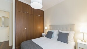 Ein Schlafzimmer mit einem großen Bett, einem Kleiderschrank und einem Nachttisch mit einer Lampe.