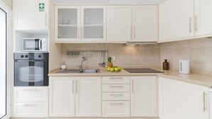 Eine moderne Küche mit weißen Schränken, einer Mikrowelle, einem Backofen und einer Obstschale auf der Arbeitsplatte.