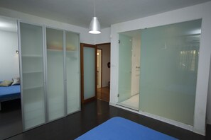A modern room with a bed, a blue mat, a wardrobe, and a door leading to another room.