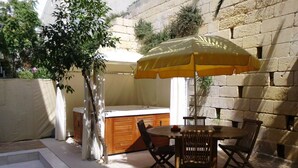 An outdoor patio with a wooden table and chairs, a yellow umbrella, and a hot tub. - Nightlife but quiet area, modern large home, bayview, garden, bbq, parking (St. George's Bay)