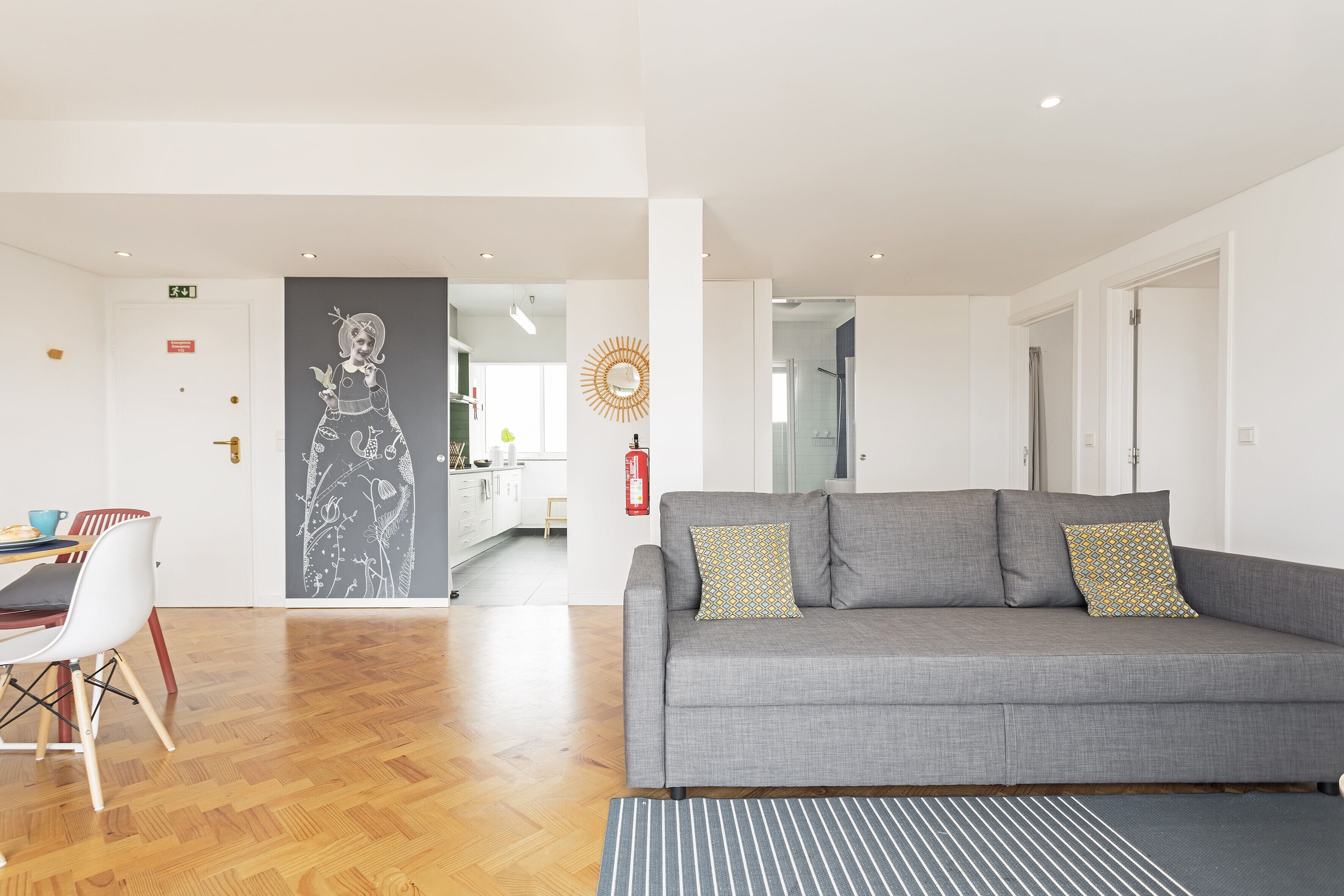 A modern living room with a grey sofa, patterned cushions, and a striped rug.