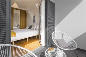 A bedroom with a bed, a chair, and a table with a teapot and cups.