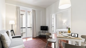 A modern hotel room with a sofa, dining table, chairs, a TV, and a balcony with curtains. - Downtown Funchal Apartments 2C 25 Fontes. (Funchal)