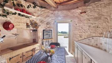 Een rustieke keuken met stenen muren, een houten plafond en uitzicht op het platteland.